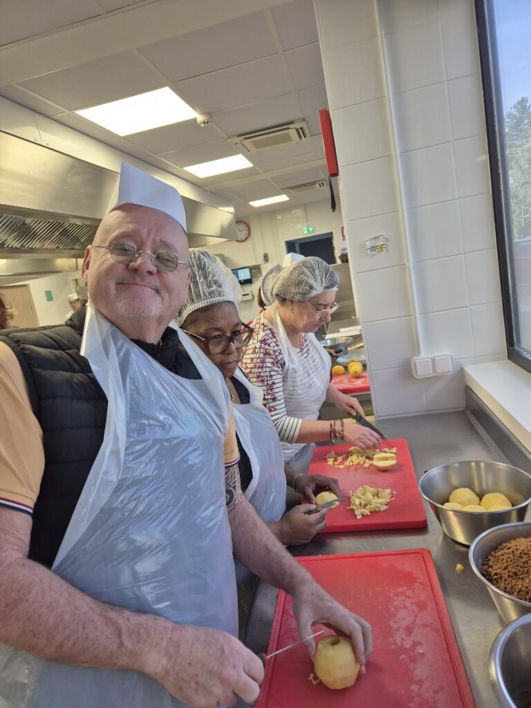 Participants du dispositif en atelier cuisine collectif, préparant un repas ensemble.